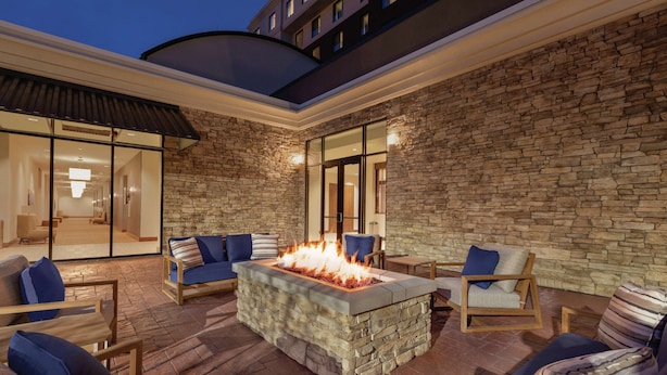 An outdoor patio with stone walls, a fire feature, and seating. - Embassy Suites by Hilton South Jordan Salt Lake City (South Jordan)