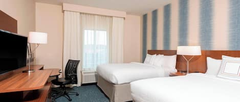 A hotel room with two beds, a desk, a chair, a TV, and a large window with curtains.