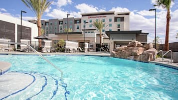 Een buitenzwembad, parasols bij het zwembad en ligstoelen