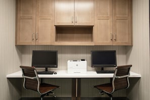 Un espace de travail équipé de deux écrans, d’une imprimante et de deux chaises de bureau.
