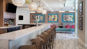 Une cuisine moderne avec un coin bar, des tabourets de bar et des œuvres d’art colorées accrochées aux murs.