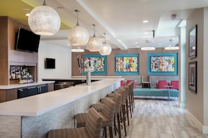 A modern kitchen with a bar area, bar stools, and colorful artwork on the walls. - Hilton Garden Inn Las Vegas City Center (Las Vegas)
