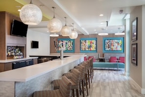 Une cuisine moderne avec un coin bar, des tabourets de bar et des œuvres d’art colorées accrochées aux murs.