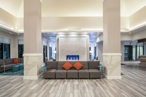 Un hall d’entrée spacieux, doté d’un grand canapé d’angle, d’une cheminée en marbre et d’un design moderne.