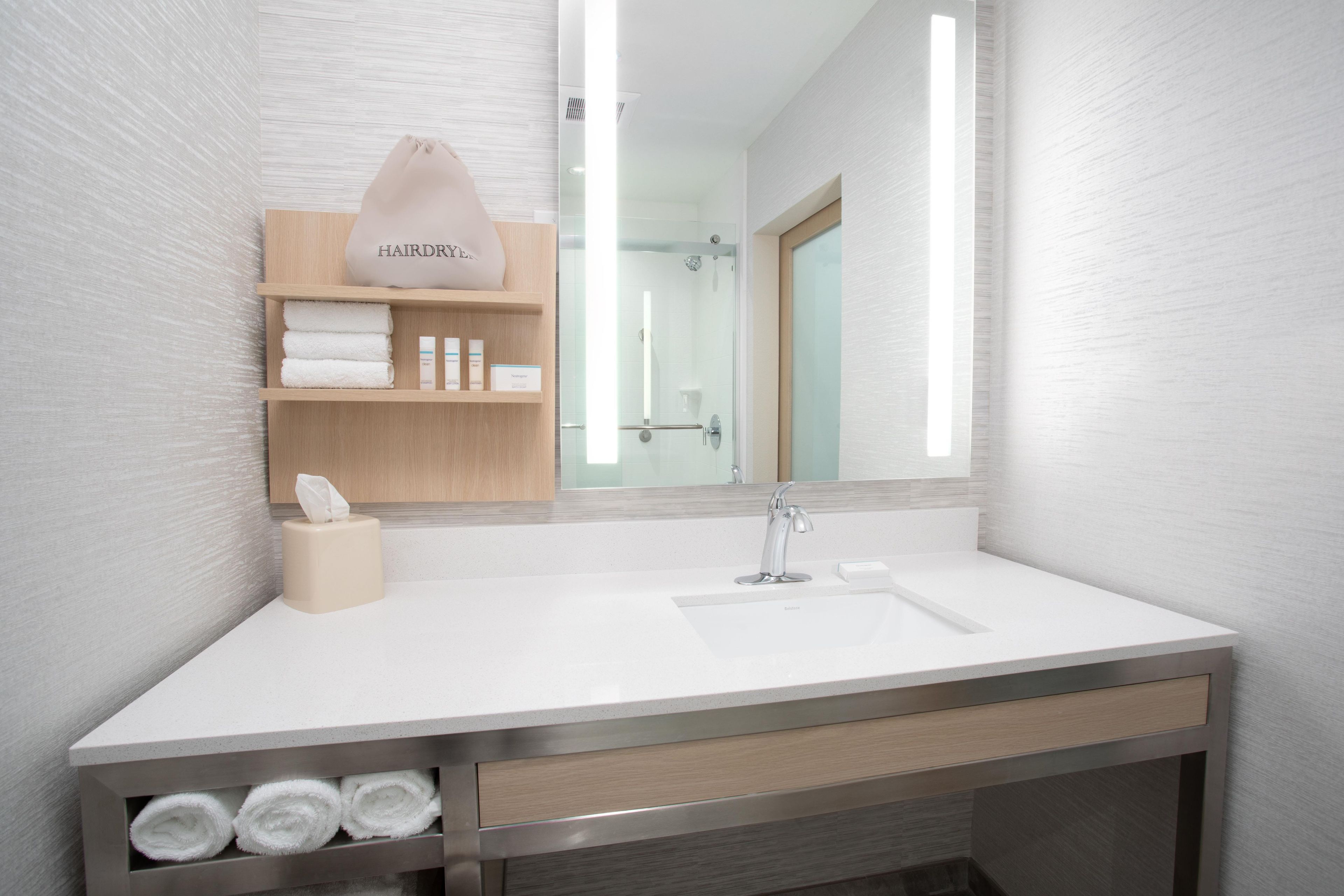 A modern bathroom with a white sink, a mirror, and a towel rack.