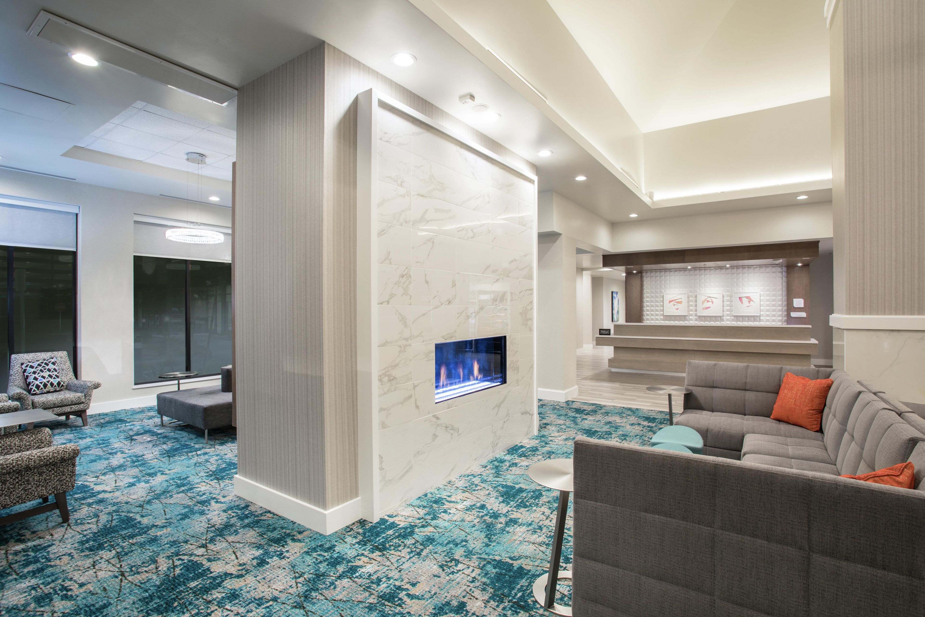 Eine moderne Hotelhalle mit Kamin, Sitzgelegenheiten und einer Rezeption.
