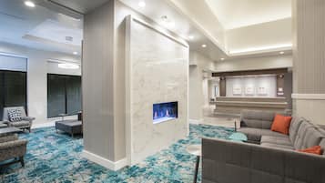 Una hall d'albergo moderna con camino, area salotto e reception.