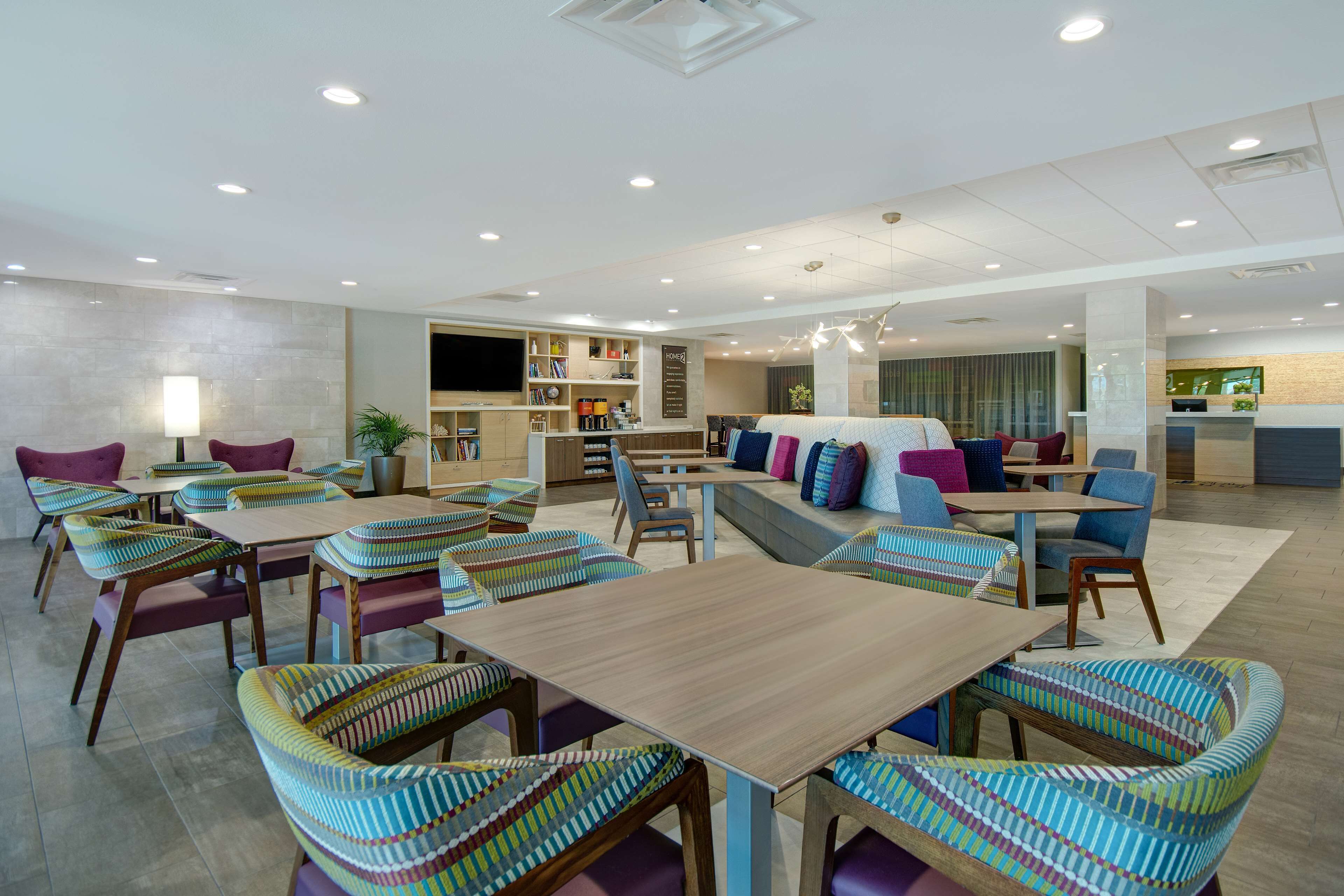 A spacious hotel lobby with multiple seating areas, including a central sofa and several tables with chairs.