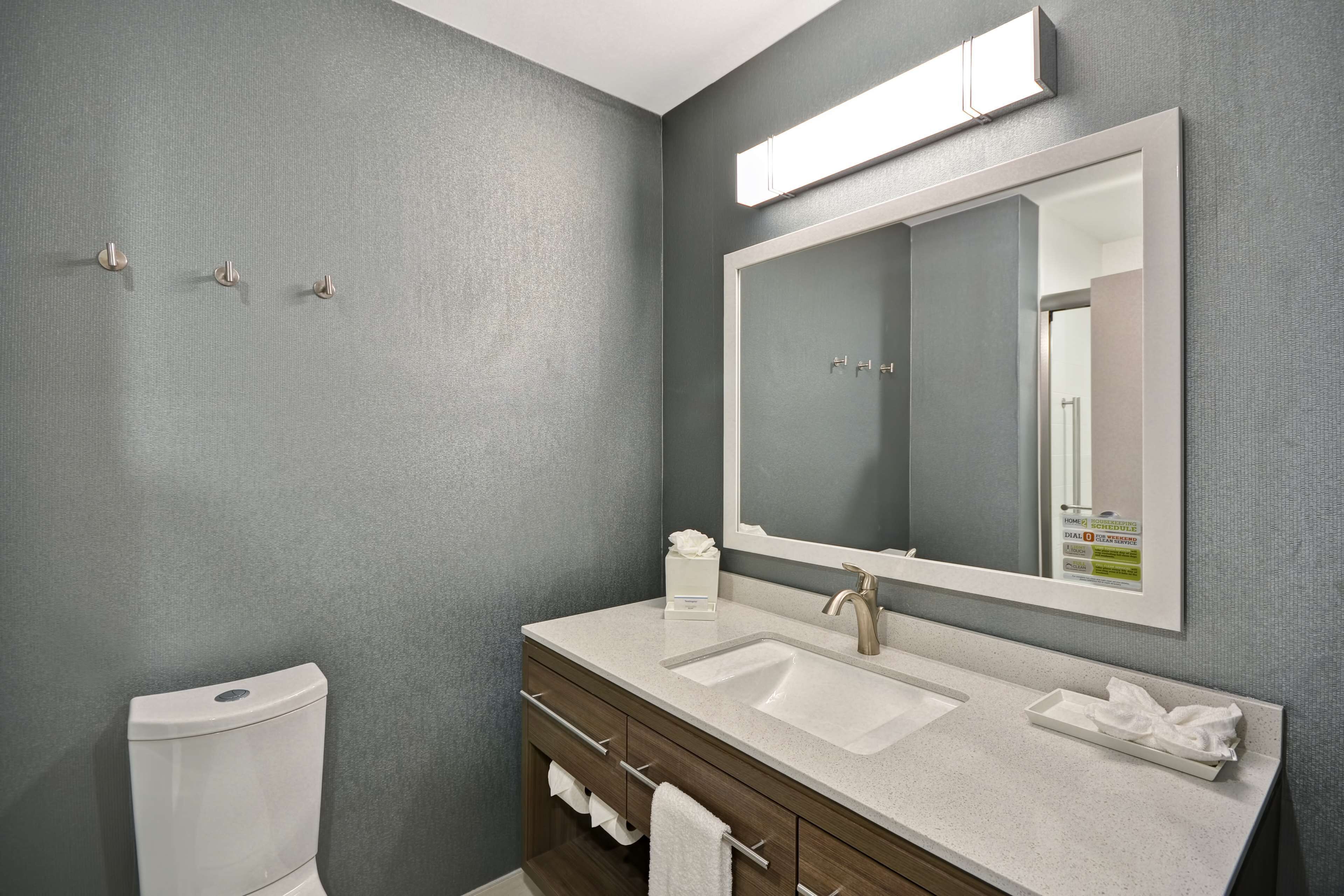 A bathroom with a toilet, a sink, a mirror, and a towel rack.