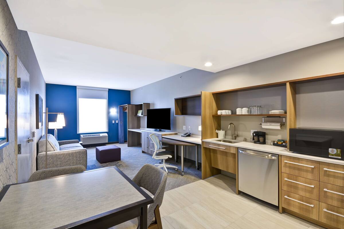 A modern kitchen with a dining area, a flat-screen TV, and a built-in microwave.