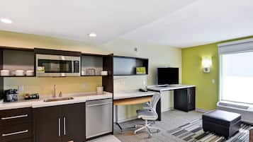 Uma cozinha compacta com eletrodomésticos modernos, área de jantar com mesa e cadeiras, e uma grande janela que oferece luz natural.