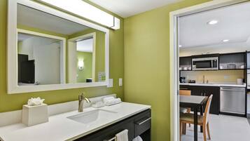A modern bathroom with a white sink, a large mirror, and a green wall.
