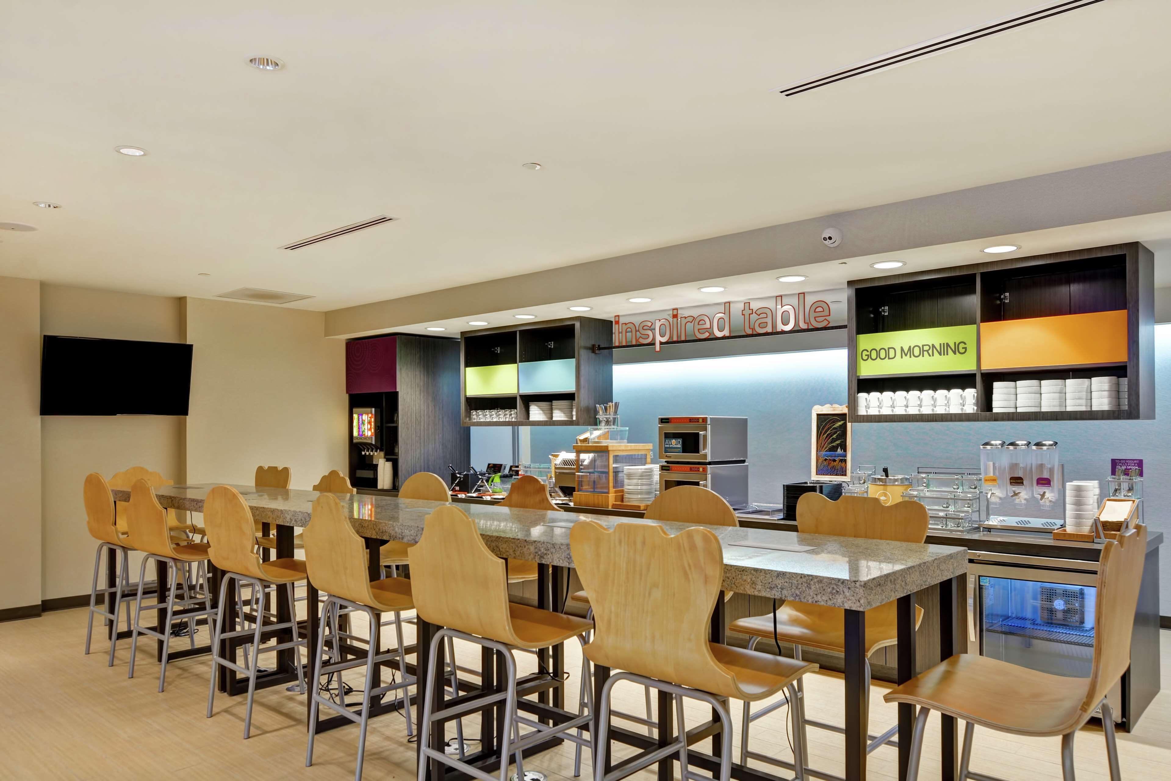 A modern cafe with multiple tables and chairs, a coffee machine, and a menu board.