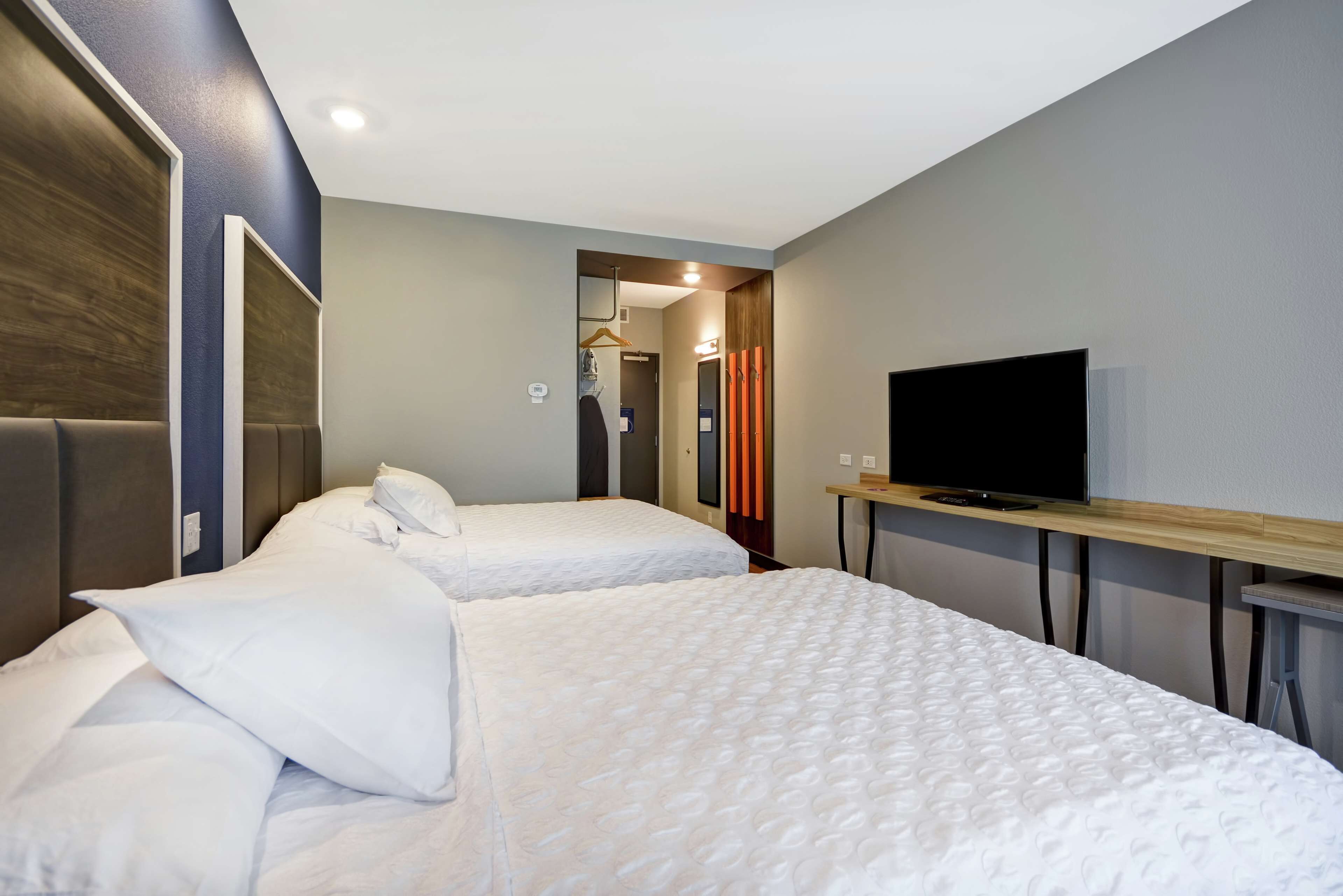 Habitación de hotel con dos camas, un televisor y un espejo.