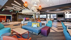 A modern lounge area with sofas, tables, and a bar. - Tru by Hilton Sumter (Sumter)