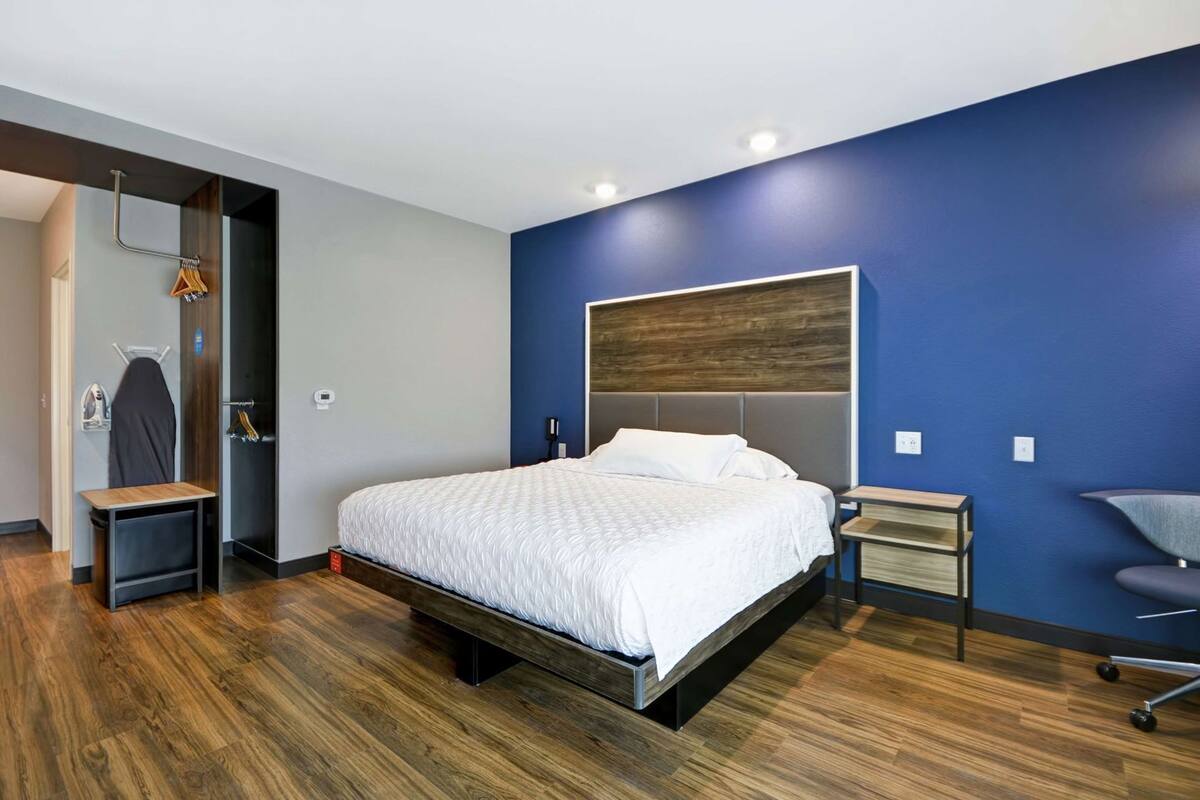 A modern bedroom with a bed, bedside tables, a chair, and a wardrobe.