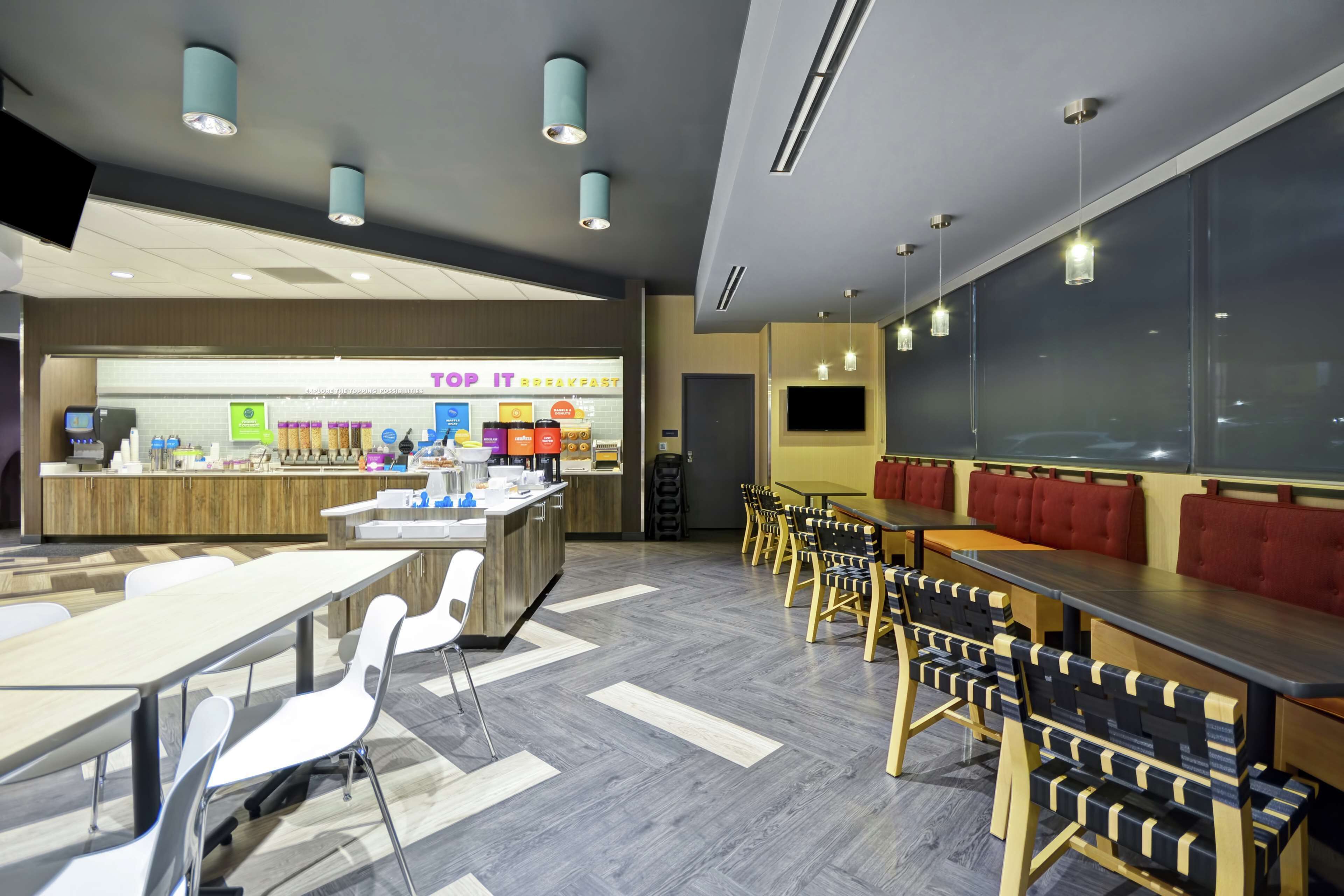 A modern dining area with tables and chairs, a counter with a menu, and a large window.