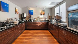 A modern kitchen with wooden cabinets, a central island, and various appliances. - Comfort Inn St. Louis Airport (Bridgeton)