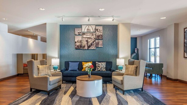 A modern living room with a sofa set, two armchairs, a coffee table, and a wall art piece. - Comfort Inn St. Louis Airport (Bridgeton)
