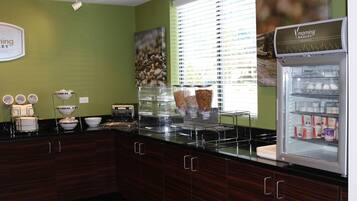 A kitchen with a refrigerator, a coffee machine, and a bowl of fruit.