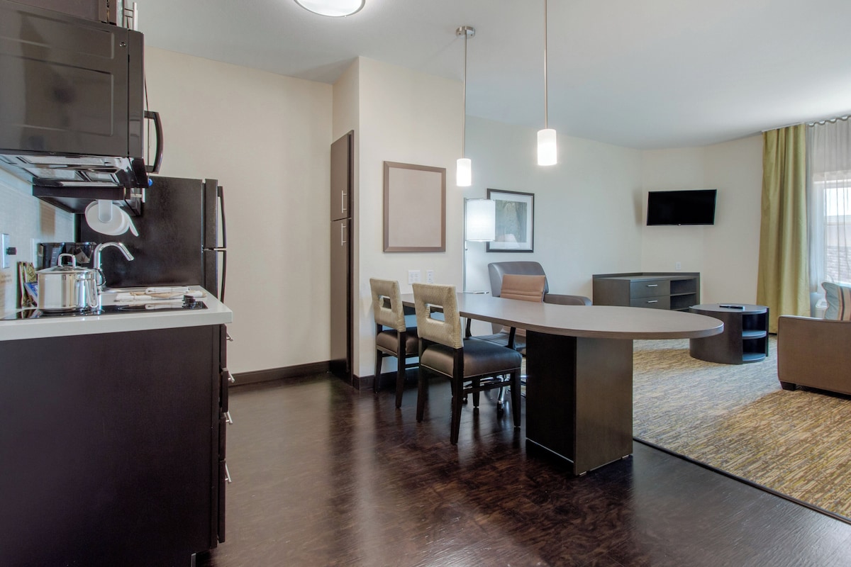 A modern kitchen with a dining area, a flat-screen TV, and a seating arrangement.