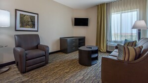 A hotel room with a sofa, armchair, TV, and a small table. - Candlewood Suites San Antonio Lackland AFB Area by IHG (San Antonio)