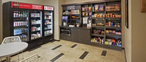 A vending area with Coca-Cola and Candlewood Cupboard machines, a microwave, and a variety of snacks and beverages.