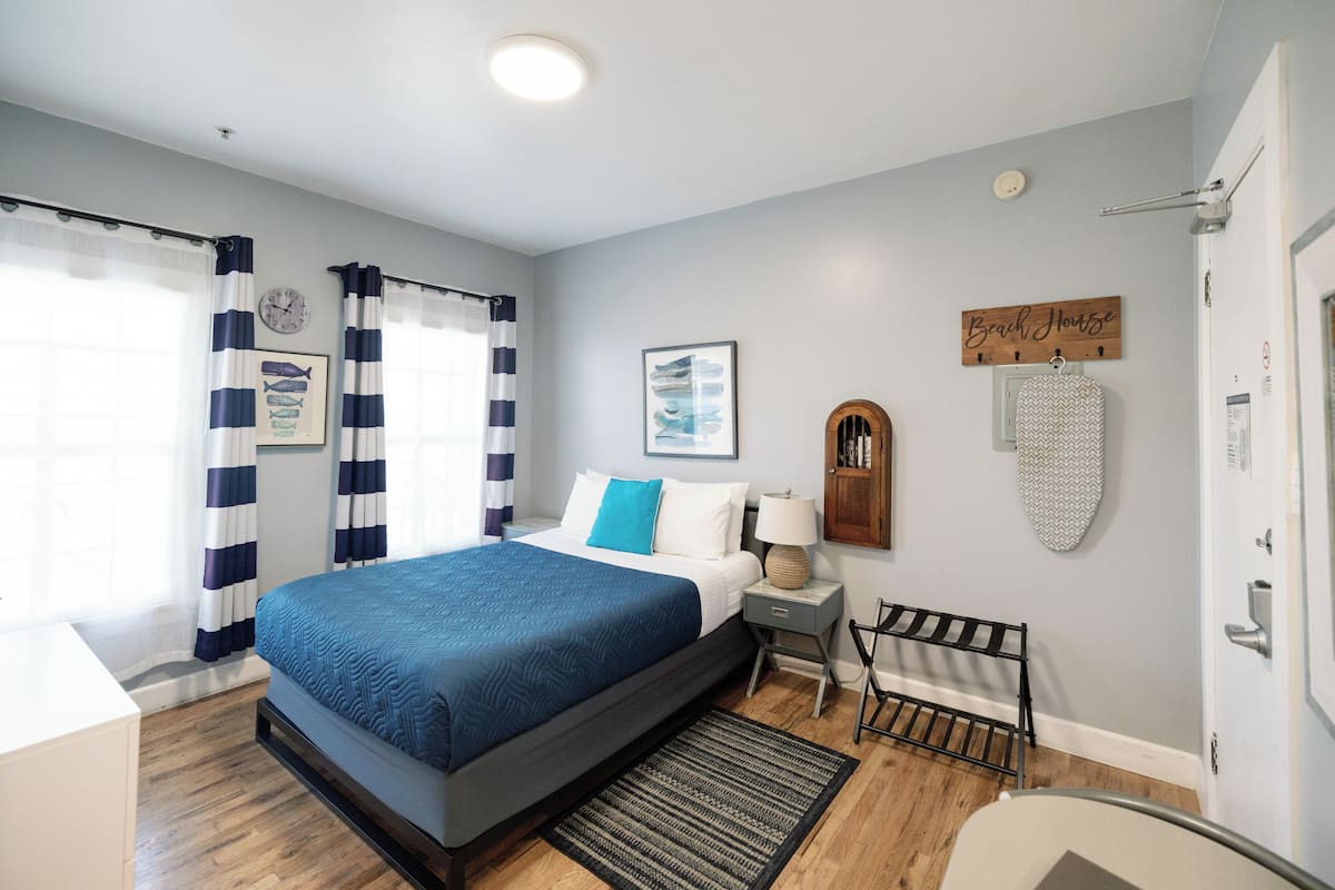 Une chambre à coucher comprenant un lit, une table de chevet, une chaise, un panneau en bois et une horloge murale.