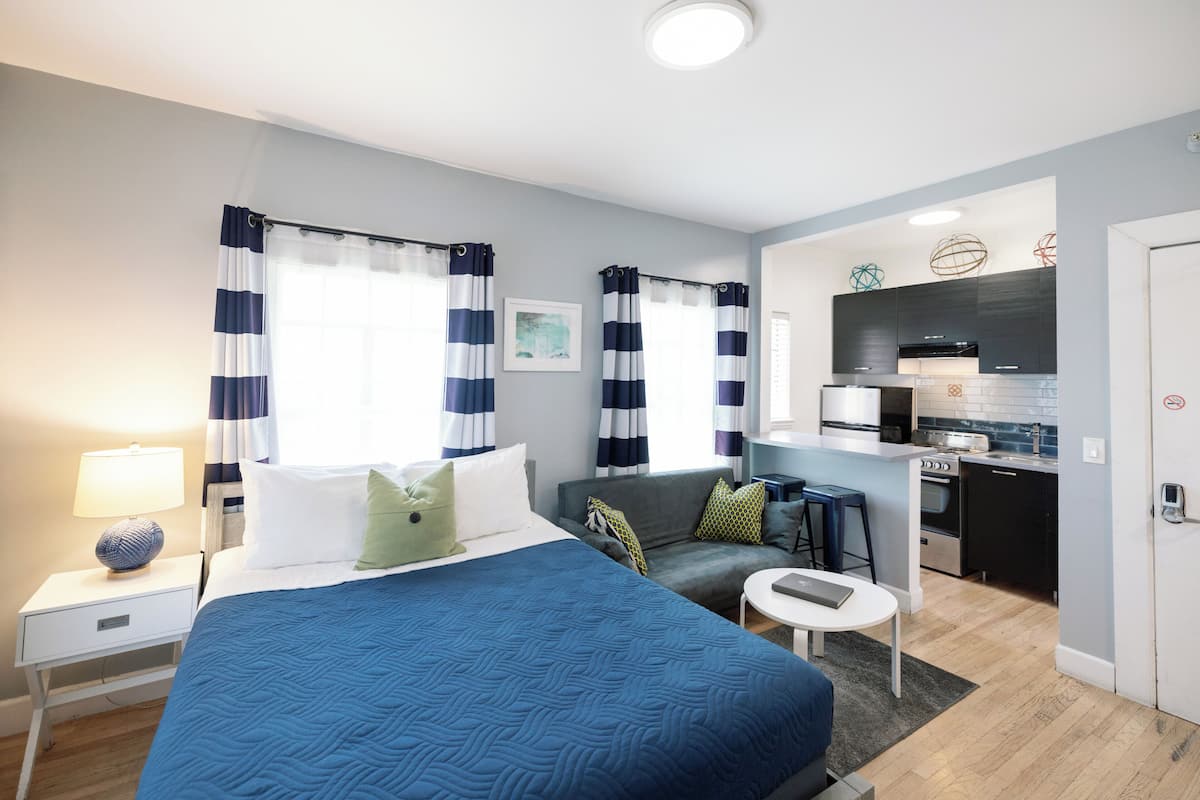 Une chambre d’hôtel moderne dotée d’un grand lit, d’un canapé, d’un petit coin cuisine et d’une salle de bain.
