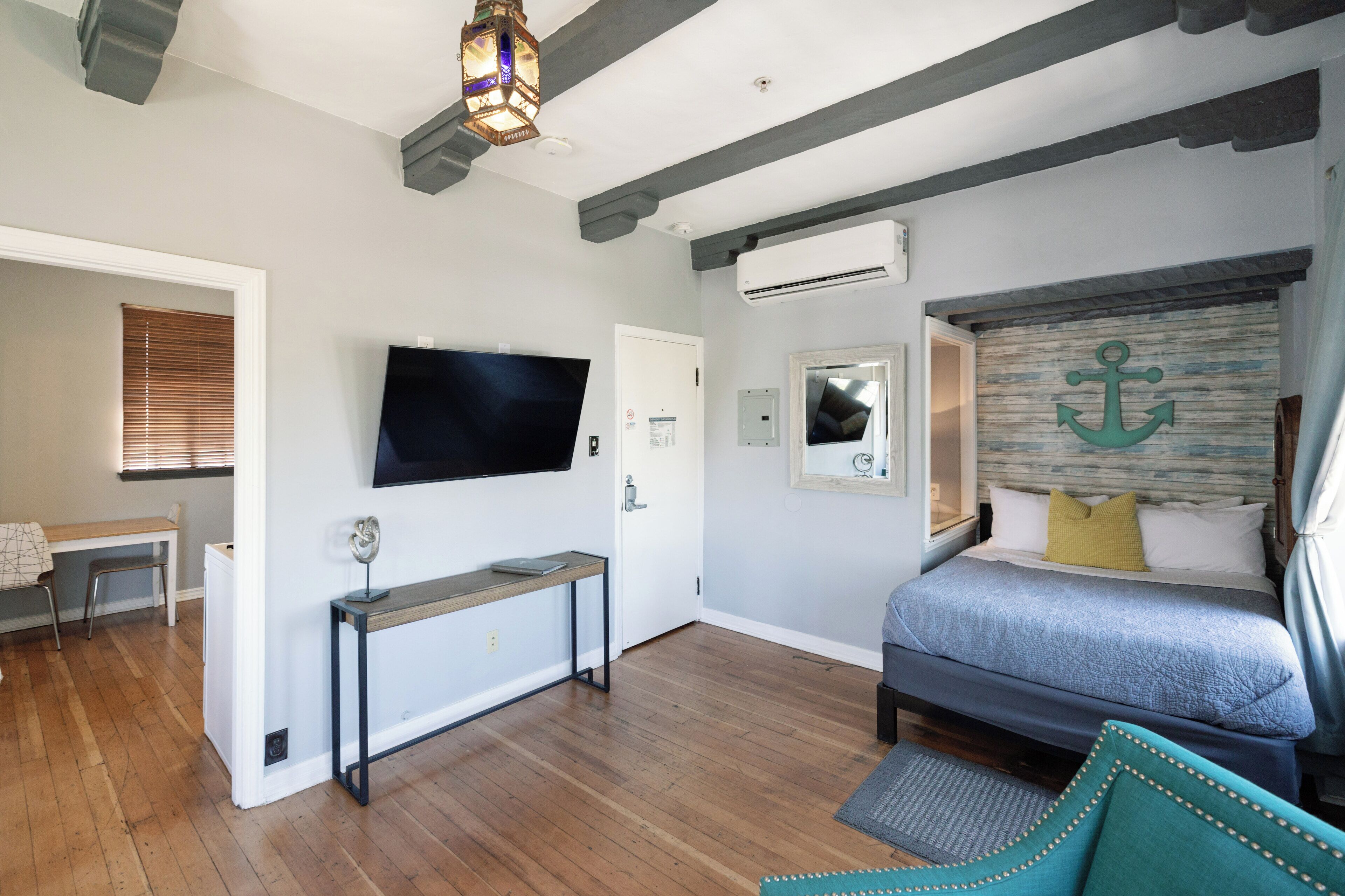 Un dormitorio con cama, televisor, escritorio y aire acondicionado.