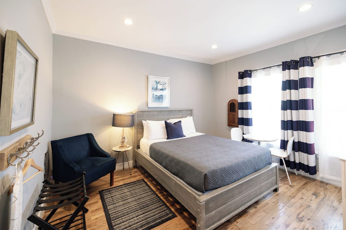 Une chambre à coucher avec un lit, une chaise, une petite table et une lampe.
