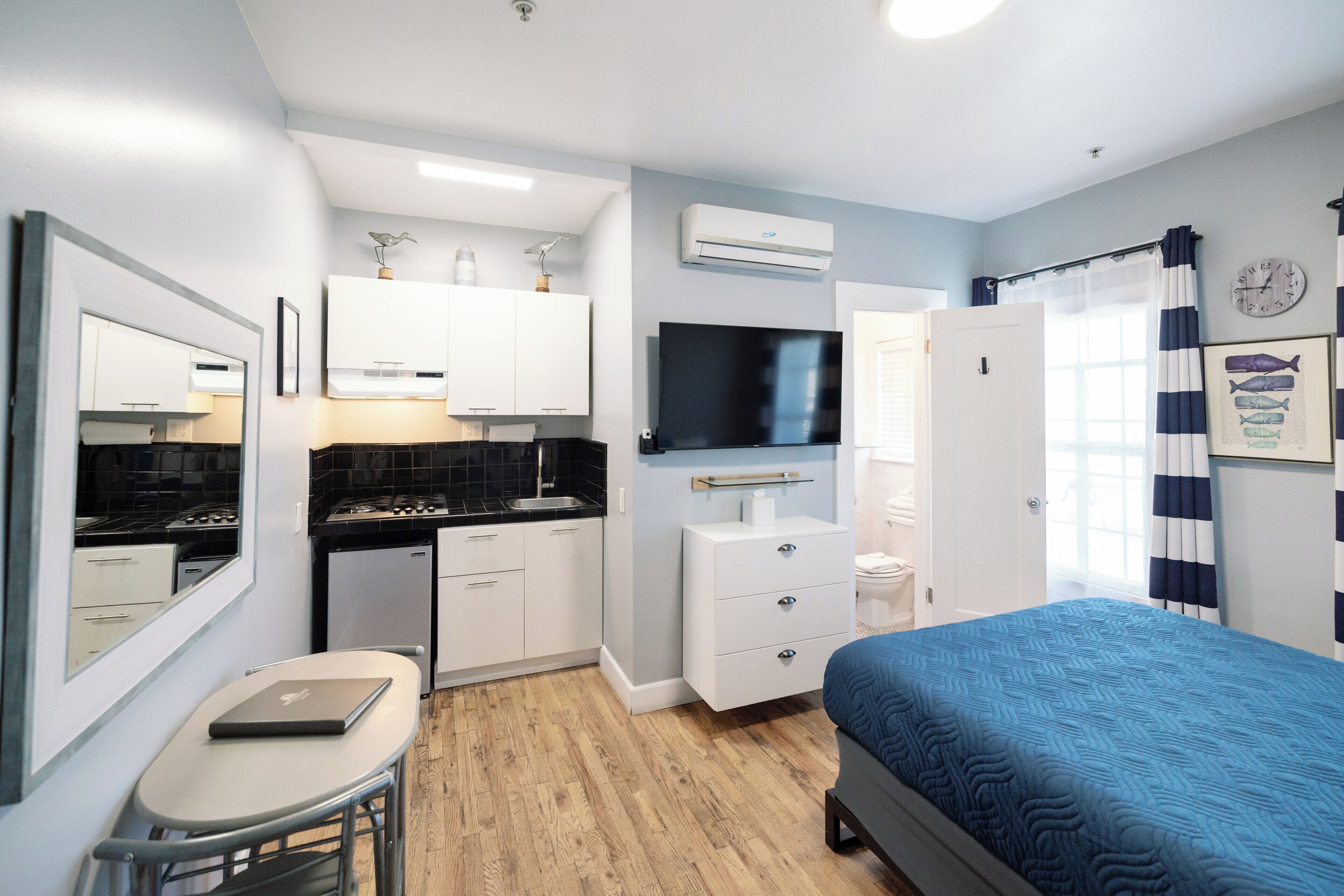 A compact room with a kitchenette, a bed, a TV, and a small table.