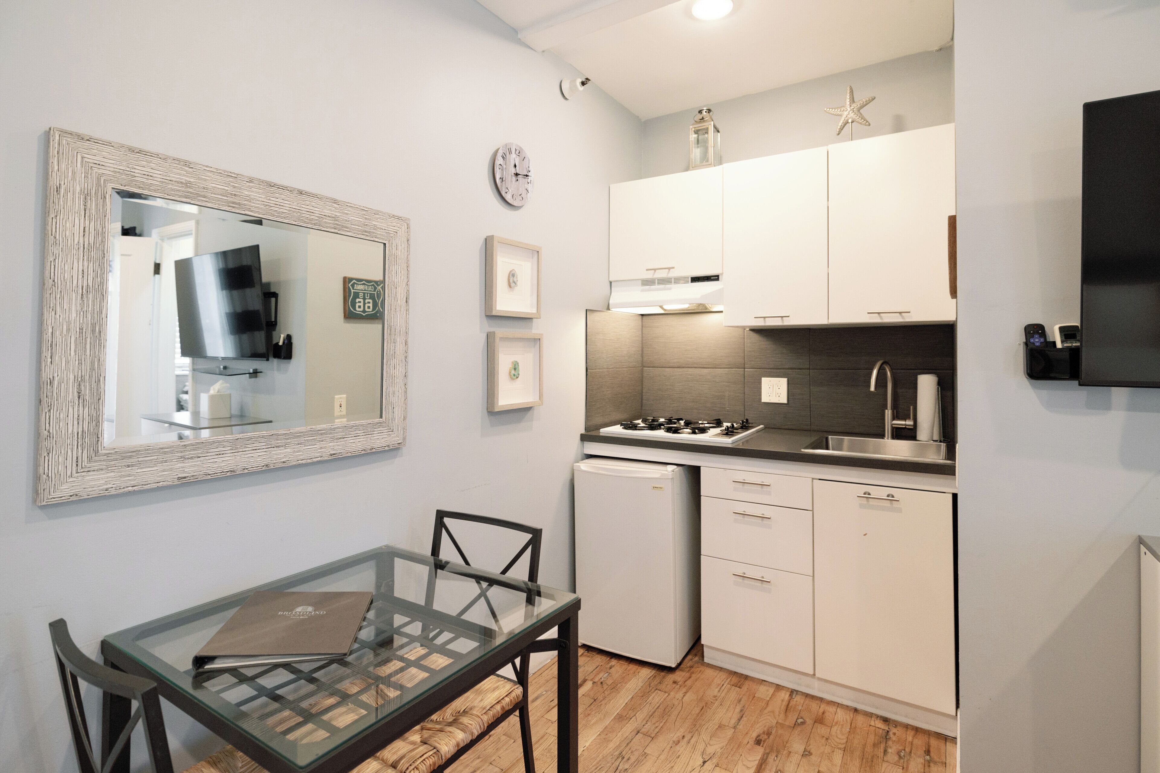 Una cocina compacta con armarios blancos, una estufa integrada y un refrigerador pequeño.