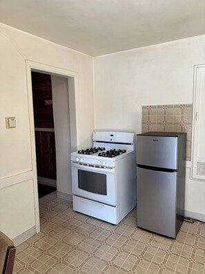 A kitchen with a white stove, a silver refrigerator, and a tiled backsplash. - Cody Motel Rock Springs WY (Rock Springs)