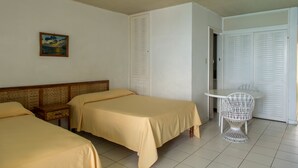 A hotel room with two beds, a small table, a chair, and a wardrobe. - Sunset Beach Studio At Montego Bay Club Resort (Montego Bay)