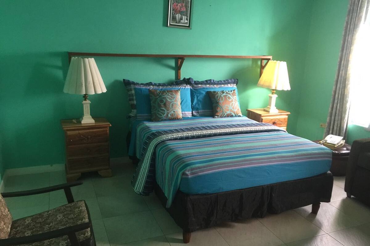 A bedroom with a bed, two nightstands, a chair, and a lamp.