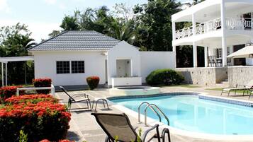 Alberca al aire libre, sombrillas en la alberca y camastros