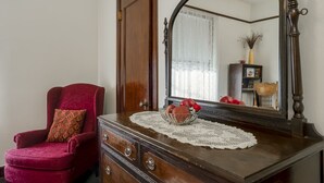 A wooden dresser with a mirror, a red chair, and a bowl of fruit. - Ryan Hotel (Wallace)