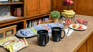 A breakfast setup with a variety of food items, including fruits, biscuits, and coffee mugs on a wooden table. - Ryan Hotel (Wallace)