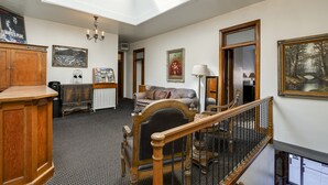 A spacious room with a high ceiling, a skylight, a wooden staircase, a sofa, a lamp, and a framed picture on the wall. - Ryan Hotel (Wallace)