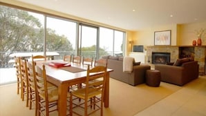Una sala de estar moderna con comedor, ventanas amplias, chimenea y balcón.