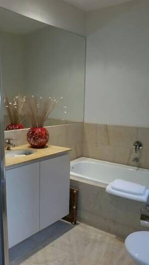 A bathroom with a sink, mirror, and bathtub. - Mark II 4 West (Mount Buller)