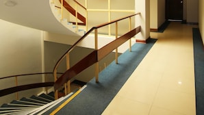 A modern hotel interior with a curved staircase, a long hallway, and a door at the end. - Hotel Pacifico Miraflores (Lima)