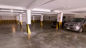 A multi-level parking garage with white pillars and yellow and black striped safety lines. - Hotel Pacifico Miraflores (Lima)