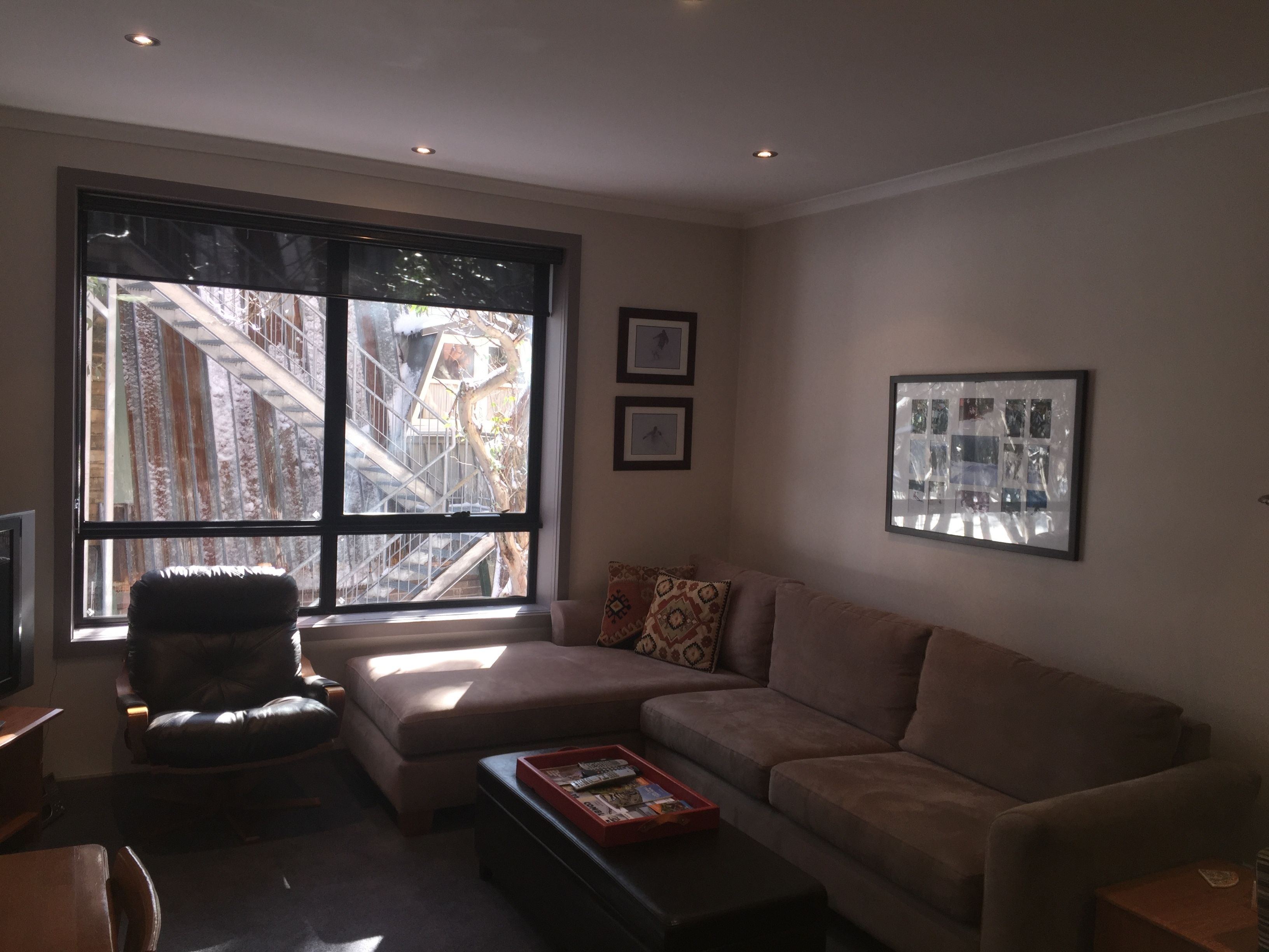 Una sala de estar con un ventanal grande, un sofá, una mesa de centro y un televisor.