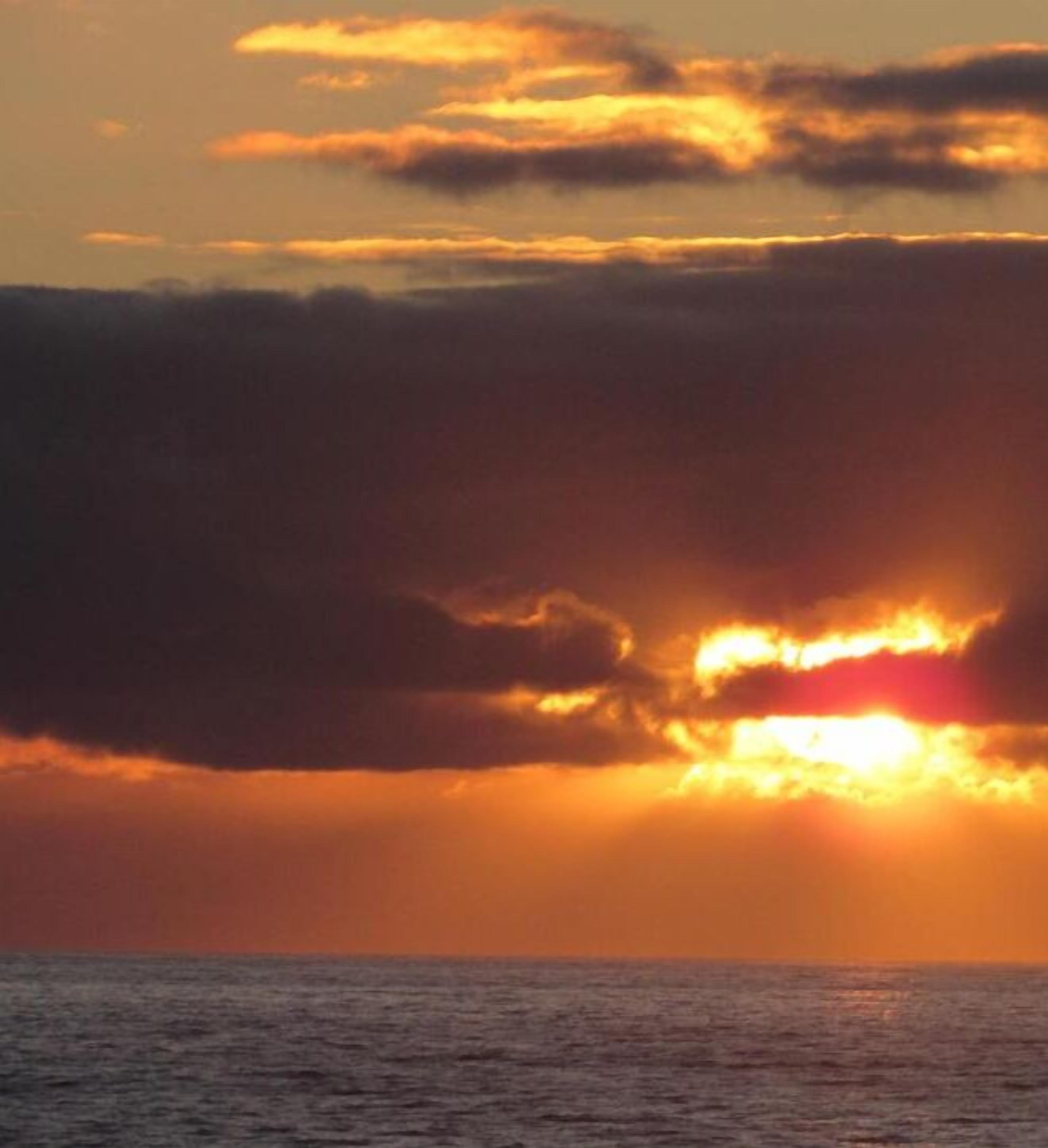 Een zonsondergang boven de oceaan met wolken.