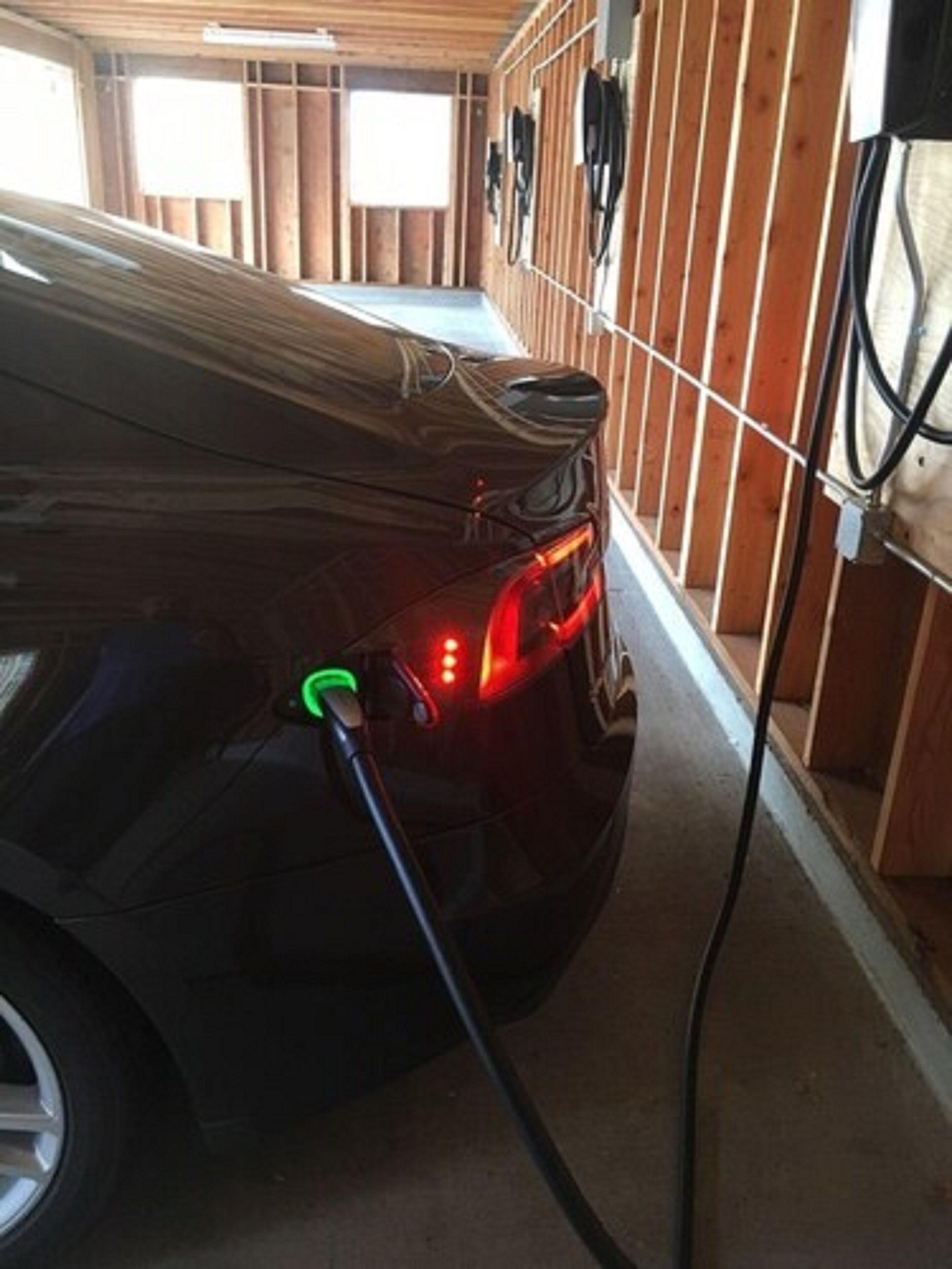 A car charging inside a building with wooden walls and a concrete floor.