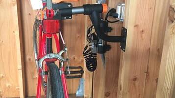A red bicycle parked inside a wooden structure with a metal railing and a black object on the wall.