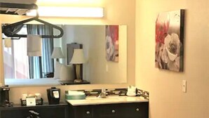 A hotel room with a large mirror, a flat-screen TV, a desk with a chair, and a bed. - The Waldport Inn (Waldport)