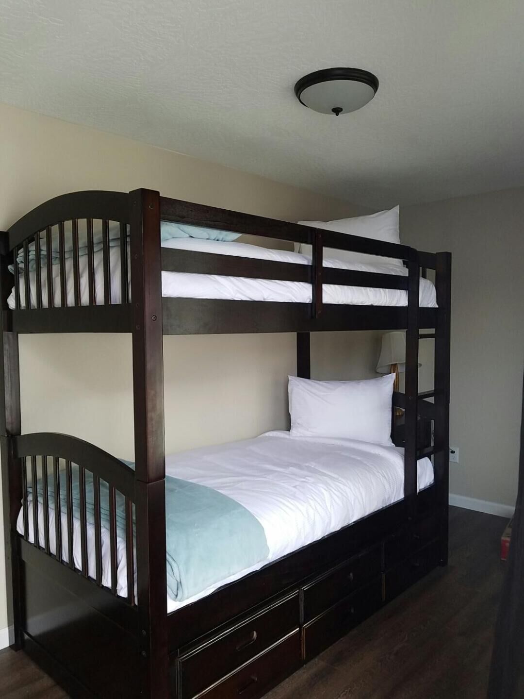 A bunk bed with a headboard, a bedside table, and a lamp.